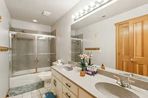 Bathroom with shower / bath combination with glass door, double vanity, light tile patterned floors, and recessed lighting