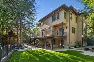 Rear view of property featuring stucco siding, a patio, stairway, and a gazebo