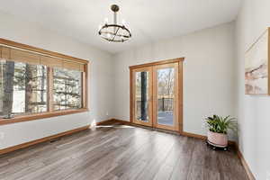 Unfurnished room featuring french doors, hanging lights, and light wood finished floors
