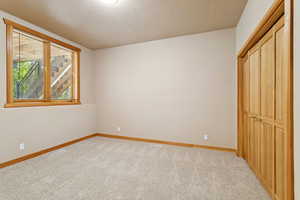 Unfurnished bedroom featuring a closet and light carpet
