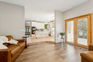 Living area with french doors, light wood-style floors, and recessed lighting