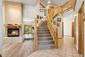 Stairs featuring a high ceiling, a glass covered fireplace, wood finished floors, a chandelier, and french doors