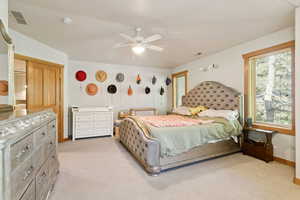 Bedroom with light colored carpet and a ceiling fan