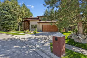 Prairie-style home featuring concrete driveway, a front lawn, stucco siding, and a chimney