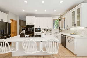 Kitchen with light stone countertops, white cabinetry, light tile patterned floors, recessed lighting, and backsplash