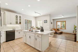 Kitchen featuring glass insert cabinets, white cabinets, backsplash, black appliances, and a kitchen island