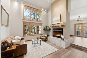Living area with a high ceiling, a fireplace, wood finished floors, french doors, and a chandelier