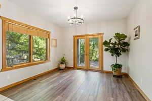 Doorway with plenty of natural light, wood finished floors, a chandelier, and french doors