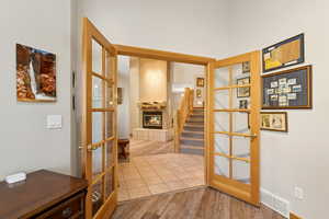 Hallway with wood finished floors, stairs, and french doors