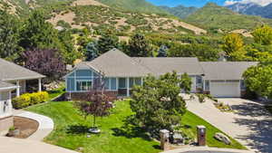 View of front of home with a garage, driveway, a shingled roof, a front yard, and a mountain view