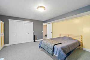 Carpeted bedroom featuring a textured ceiling and a closet