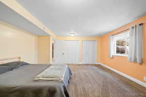 Carpeted bedroom featuring multiple closets and a textured ceiling
