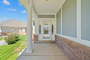 Property entrance with covered porch, a yard, and stucco siding