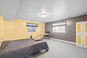 Carpeted bedroom featuring baseboards and a textured ceiling