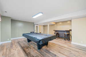 Rec room with pool table, light wood-type flooring, and a bar