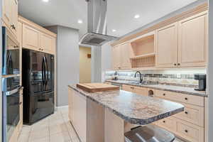 Kitchen with light brown cabinets, stainless steel appliances, tasteful backsplash, open shelves, and recessed lighting