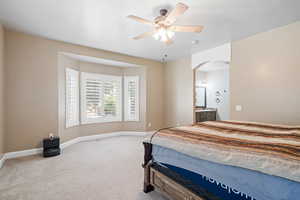 Carpeted bedroom with ceiling fan, arched walkways, and connected bathroom