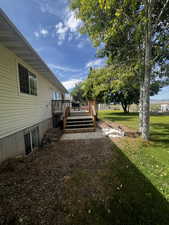 View of green lawn with a wooden deck and stairway