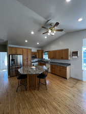Kitchen with appliances with stainless steel finishes, brown cabinetry, plenty of natural light, a breakfast bar area, and recessed lighting