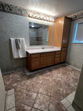 Full bath featuring, a textured ceiling, vanity, a stall shower, and tile patterned floors