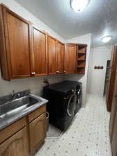 Laundry room featuring light flooring, cabinet space, independent washer and dryer, and a textured ceiling