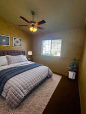 Carpeted bedroom featuring vaulted ceiling and a ceiling fan