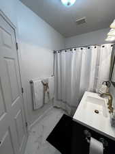 Bathroom with vanity, light marble finish floors, a textured ceiling, and a shower with curtain