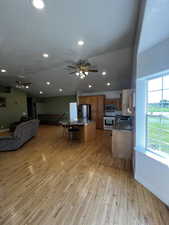 Kitchen featuring open floor plan, a breakfast bar area, a textured ceiling, light wood-style flooring, and stainless steel appliances