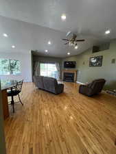 Living area with a textured ceiling, recessed lighting, a fireplace, lofted ceiling, and light wood finished floors