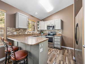 Kitchen with vaulted ceiling, stainless steel appliances, tasteful backsplash, a peninsula, and open shelves