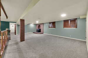 Finished basement with a wood stove and light carpet