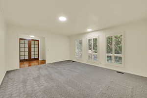 Spare room with french doors, light carpet, crown molding, and recessed lighting