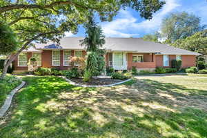 Single story home with a porch, brick siding, and a front yard