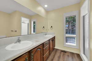 Bathroom featuring a stall shower, double vanity, dark wood-type flooring, and recessed lighting