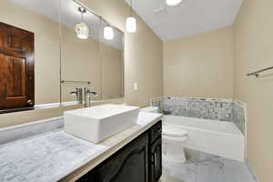 Full bathroom featuring vanity, light marble finish flooring, and a bath