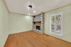 Unfurnished living room featuring crown molding, light wood-style flooring, a fireplace, and recessed lighting