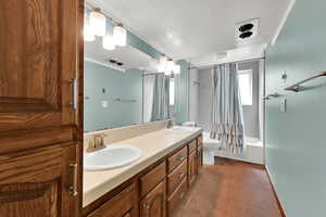 Bathroom with shower / bath combination with curtain, double vanity, dark tile patterned floors, a textured ceiling, and ornamental molding