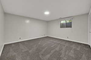 Carpeted spare room featuring baseboards
