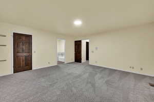 Unfurnished bedroom with light colored carpet and connected bathroom