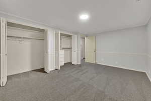 Unfurnished bedroom with multiple closets, carpet, and crown molding