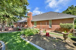 Back of property featuring brick siding, a shingled roof, a chimney, a yard, and a patio