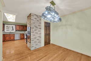 Unfurnished dining area with light wood-type flooring and ornamental molding