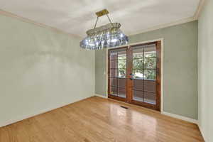 Unfurnished dining area featuring ornamental molding, french doors, and wood finished floors