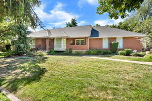 Ranch-style home featuring brick siding, a front lawn, a shingled roof, and a porch