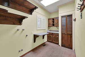 Laundry area with light tile patterned floors, crown molding, hookup for a gas dryer, and hookup for a washing machine