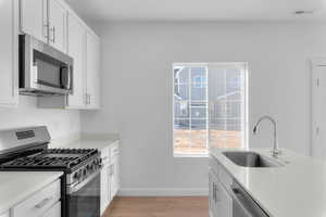 Kitchen featuring stainless steel appliances, white cabinetry, and light wood-style flooring