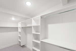 Walk in closet with light colored carpet