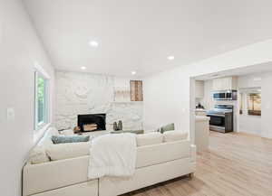 Living area featuring light wood-style flooring, a fireplace, and recessed lighting