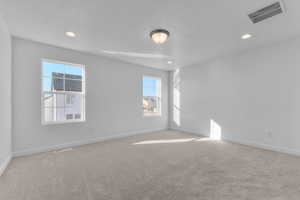 Unfurnished room featuring a textured ceiling, light colored carpet, and recessed lighting