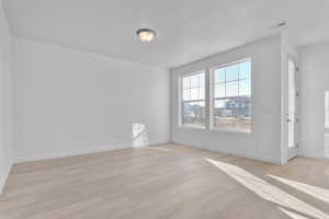Empty room featuring light wood-style floors and a textured ceiling